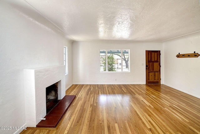 2421 E Drachman St, Tucson, AZ 85719 - unfurnished living room with a fireplace with raised hearth, wood finished floors, and a textured ceiling