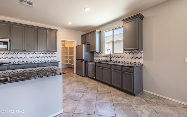 8820 E Stone Meadow Cir, Tucson, AZ 85730 - kitchen with appliances with stainless steel finishes, dark stone counters, backsplash, light tile patterned flooring, and recessed lighting