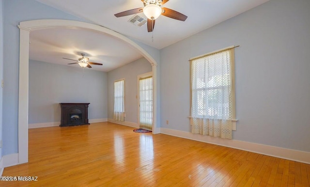 201 B St, Bisbee, AZ 85603 - unfurnished living room with ceiling fan, arched walkways, light wood-style flooring, and a wood stove