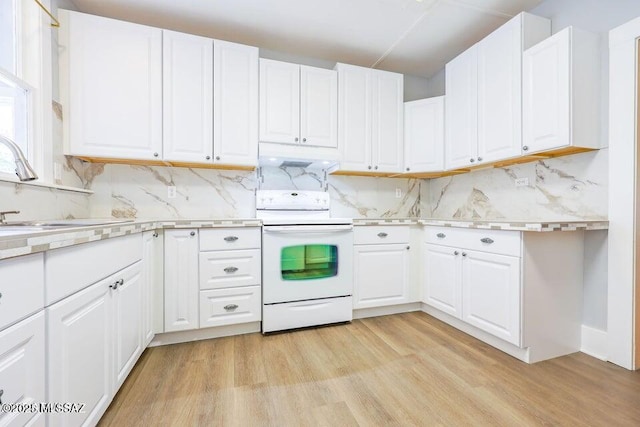 201 B St, Bisbee, AZ 85603 - kitchen with white electric stove, light countertops, light wood-type flooring, decorative backsplash, and white cabinetry
