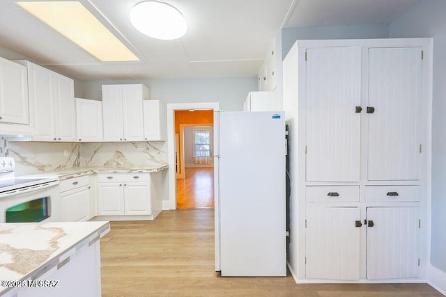 201 B St, Bisbee, AZ 85603 - kitchen featuring white appliances, light wood-type flooring, white cabinetry, decorative backsplash, and custom exhaust hood