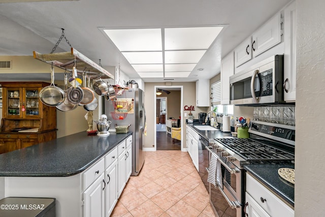 1939 S San Vincent Dr, Green Valley, AZ 85614 - kitchen with appliances with stainless steel finishes, white cabinetry, dark countertops, and light tile patterned floors