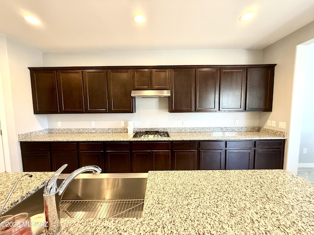 9636 N Havenwood Way, Marana, AZ 85653 - kitchen with stainless steel gas stovetop, under cabinet range hood, dark brown cabinets, light stone countertops, and recessed lighting