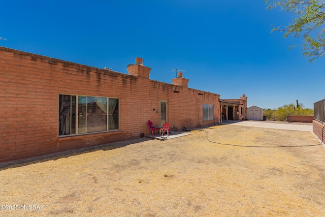 10901 N Camino De Oeste, Tucson, AZ 85742 - rear view of property featuring a storage shed, a chimney, and brick siding