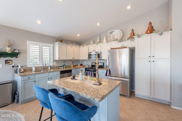 9908 E Shadow Glen Ct, Tucson, AZ 85748 - kitchen with appliances with stainless steel finishes, light tile patterned floors, lofted ceiling, a kitchen island, and light stone countertops