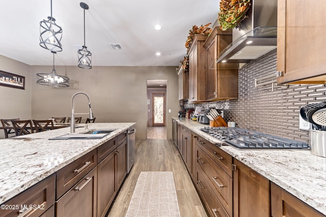 3188 W Tumamoc Dr, Tucson, AZ 85745 - kitchen featuring wall chimney range hood, light wood-style floors, appliances with stainless steel finishes, decorative backsplash, and light stone countertops