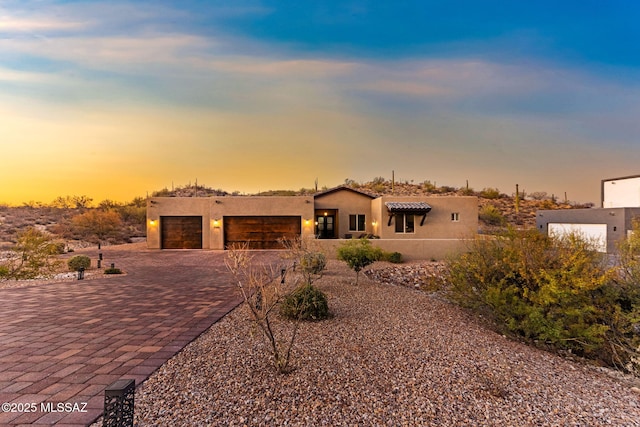 3188 W Tumamoc Dr, Tucson, AZ 85745 - pueblo-style home with decorative driveway, stucco siding, a garage, and a tile roof
