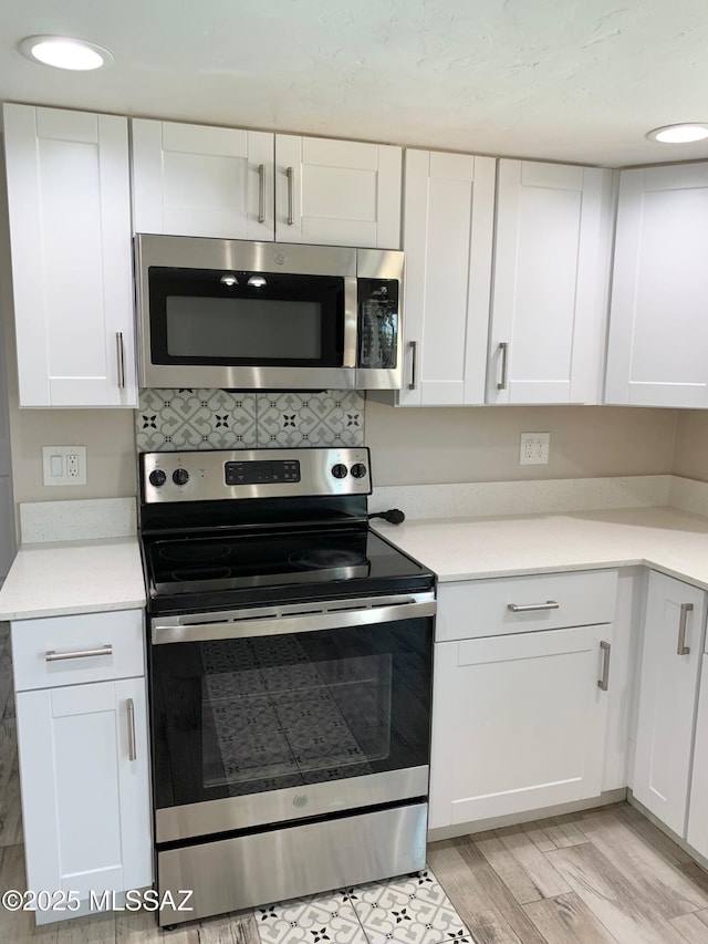 2973 S Kolb Rd, Tucson, AZ 85730 - kitchen with stainless steel appliances, white cabinetry, light countertops, light wood-style flooring, and decorative backsplash