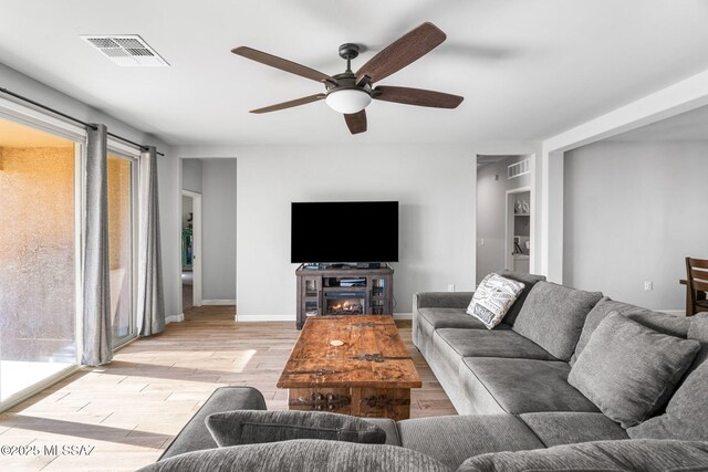 13331 N Carbine Ct, Marana, AZ 85653 - living room with ceiling fan, light wood finished floors, and a glass covered fireplace