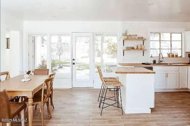 2602 E Prince Rd, Tucson, AZ 85716 - kitchen with a center island, a breakfast bar area, white cabinetry, light wood-type flooring, and light countertops