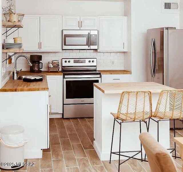2602 E Prince Rd, Tucson, AZ 85716 - kitchen with appliances with stainless steel finishes, wood counters, white cabinetry, and backsplash