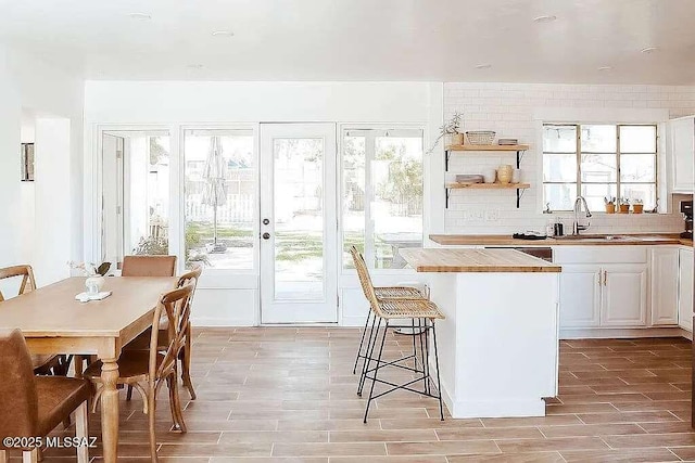 2602 E Prince Rd, Tucson, AZ 85716 - kitchen featuring open shelves, a kitchen bar, decorative backsplash, light wood finished floors, and white cabinets