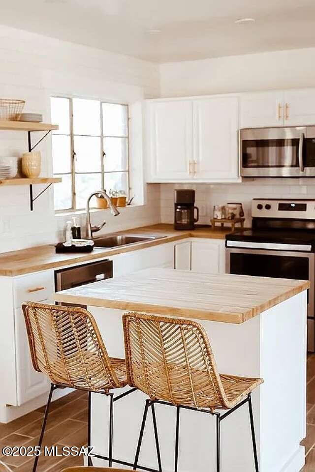 2602 E Prince Rd, Tucson, AZ 85716 - kitchen featuring stainless steel appliances, white cabinetry, a breakfast bar, and wooden counters