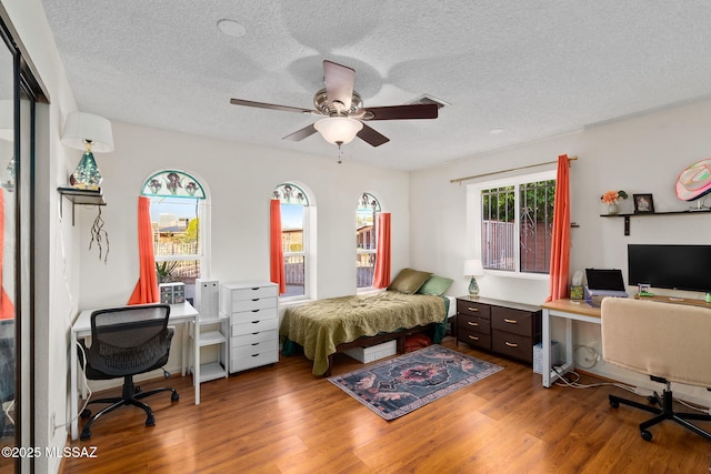 53 N Davila Cir, Tucson, AZ 85745 - bedroom featuring an office area, wood finished floors, a textured ceiling, and ceiling fan