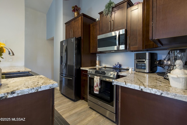 2856 W Goldfield Dr, Tucson, AZ 85745 - kitchen with appliances with stainless steel finishes, light wood-style floors, dark brown cabinetry, and light stone counters