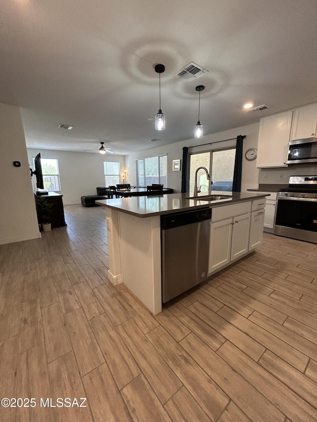 1126 E Descent St, Tucson, AZ 85719 - kitchen featuring stainless steel appliances, light wood-type flooring, open floor plan, and white cabinets