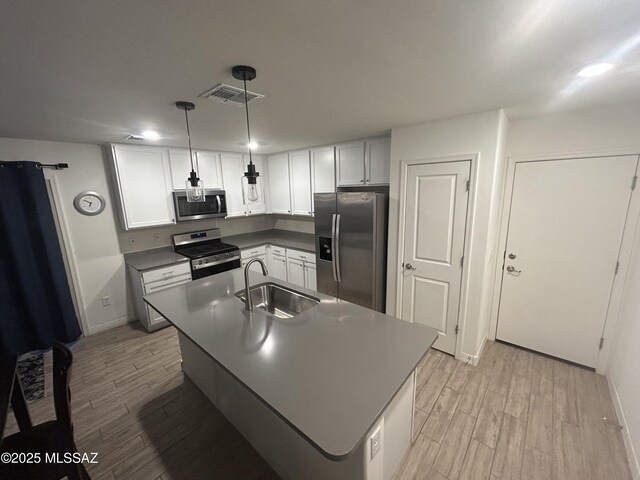 1126 E Descent St, Tucson, AZ 85719 - kitchen featuring stainless steel appliances, light wood-style flooring, dark countertops, white cabinets, and a kitchen island with sink