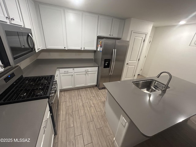 1126 E Descent St, Tucson, AZ 85719 - kitchen featuring stainless steel appliances, light wood-style flooring, white cabinetry, a center island with sink, and dark countertops
