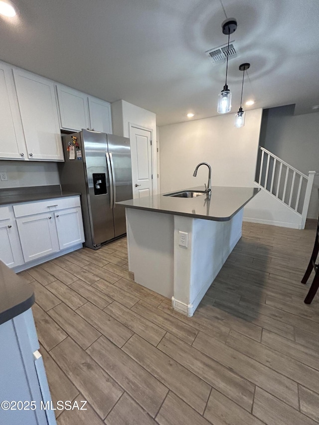 1126 E Descent St, Tucson, AZ 85719 - kitchen with stainless steel fridge, dark countertops, light wood-style flooring, and white cabinets