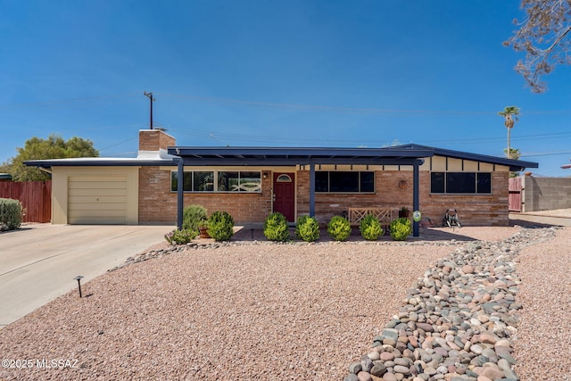 6951 E Hayne Pl, Tucson, AZ 85710 - single story home with an attached garage, concrete driveway, a chimney, roof mounted solar panels, and brick siding