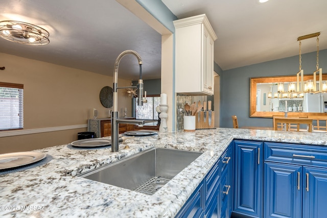 6951 E Hayne Pl, Tucson, AZ 85710 - kitchen featuring blue cabinets, white cabinetry, vaulted ceiling, light stone countertops, and a chandelier