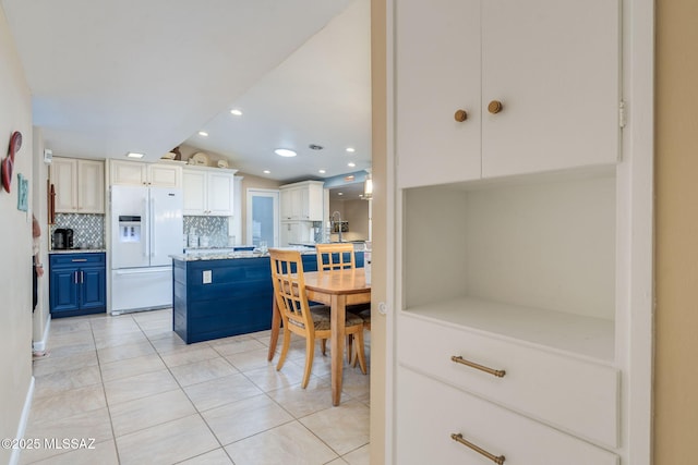 6951 E Hayne Pl, Tucson, AZ 85710 - kitchen featuring white refrigerator with ice dispenser, tasteful backsplash, light countertops, light tile patterned floors, and blue cabinetry