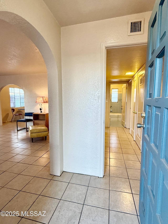 1412 E Silver St, Tucson, AZ 85719 - hall featuring light tile patterned flooring, a textured wall, and arched walkways
