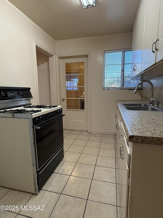 1412 E Silver St, Tucson, AZ 85719 - kitchen with black range with gas stovetop, light tile patterned flooring, and white cabinets