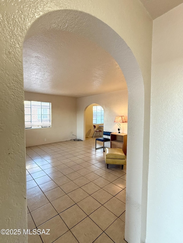1412 E Silver St, Tucson, AZ 85719 - corridor with a textured wall, light tile patterned flooring, arched walkways, and a textured ceiling