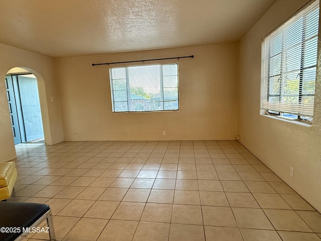 1412 E Silver St, Tucson, AZ 85719 - spare room with arched walkways, healthy amount of natural light, light tile patterned floors, and a textured ceiling