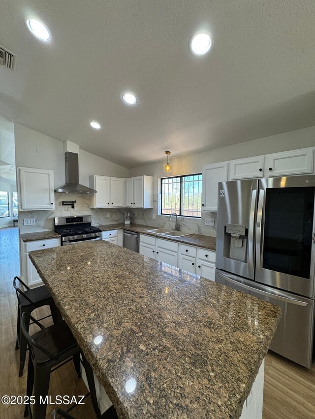 1129 W Amberbrooke Ave, Tucson, AZ 85745 - kitchen with wall chimney range hood, appliances with stainless steel finishes, white cabinetry, backsplash, and vaulted ceiling