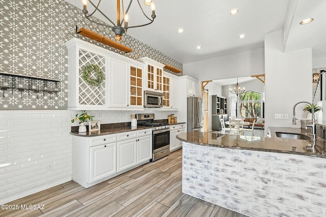 7705 W Taltson Dr, Tucson, AZ 85743 - kitchen with appliances with stainless steel finishes, a chandelier, wallpapered walls, white cabinetry, and dark stone countertops