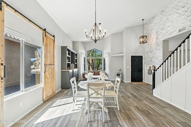 7705 W Taltson Dr, Tucson, AZ 85743 - dining room featuring a barn door, a chandelier, light wood finished floors, stairway, and a high ceiling