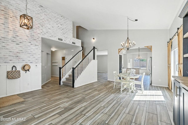 7705 W Taltson Dr, Tucson, AZ 85743 - dining room featuring a barn door, a towering ceiling, light wood-style flooring, a chandelier, and stairs