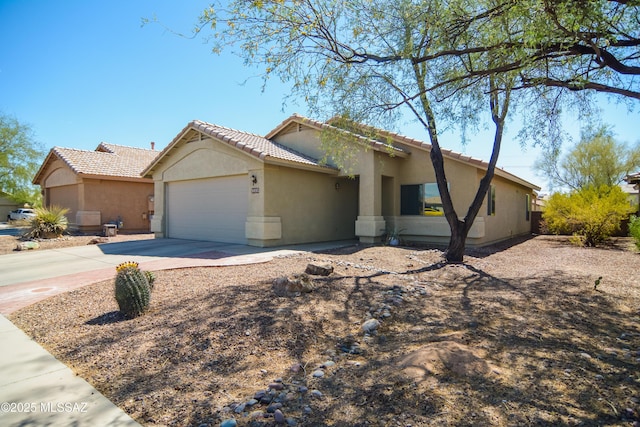 9495 N Winter Wren Ave, Tucson, AZ 85742 - view of front of house featuring an attached garage, stucco siding, driveway, and a tiled roof