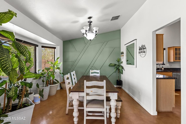 10636 E Malta St, Tucson, AZ 85747 - dining space featuring concrete floors, a chandelier, and a decorative wall