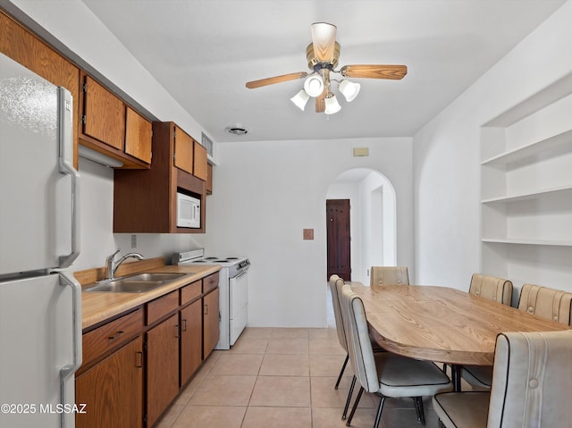 2638 N Wilson Ave, Tucson, AZ 85719 - kitchen with white appliances, arched walkways, a ceiling fan, light countertops, and brown cabinets