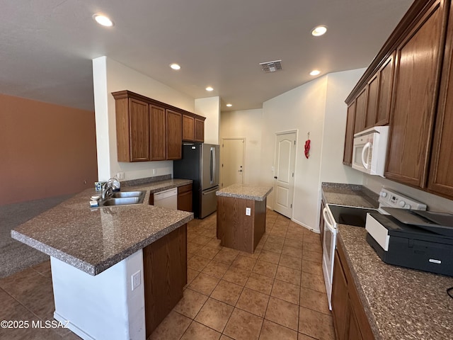 13049 N Woosnam Way, Oro Valley, AZ 85755 - kitchen featuring white appliances, a kitchen island, recessed lighting, light tile patterned floors, and a peninsula
