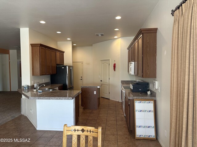 13049 N Woosnam Way, Oro Valley, AZ 85755 - kitchen with white microwave, a kitchen island, freestanding refrigerator, dark tile patterned floors, and recessed lighting