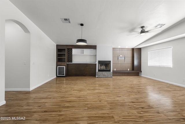 446 Soda Ln, Rio Rico, AZ 85648 - unfurnished living room featuring a ceiling fan, wood finished floors, arched walkways, lofted ceiling, and wine cooler