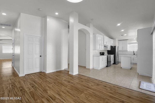 446 Soda Ln, Rio Rico, AZ 85648 - unfurnished living room featuring arched walkways, light wood-style flooring, recessed lighting, and vaulted ceiling