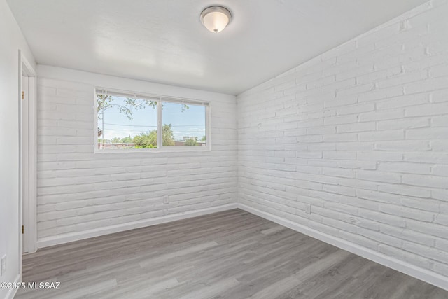 4041 E Dover Stra, Tucson, AZ 85706 - empty room featuring wood finished floors and brick wall