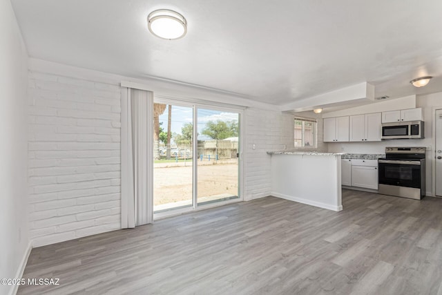 4041 E Dover Stra, Tucson, AZ 85706 - kitchen with appliances with stainless steel finishes, light wood finished floors, brick wall, a peninsula, and white cabinets