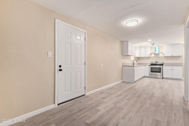2514 N Castro Ave, Tucson, AZ 85705 - kitchen featuring stainless steel electric range oven, wall chimney exhaust hood, light countertops, white cabinetry, and light wood finished floors
