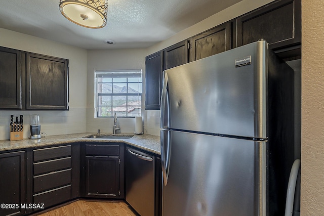 6490 N Tierra De Las Catalinas Unit 94, Tucson, AZ 85718 - kitchen featuring stainless steel appliances, light wood-style flooring, a textured ceiling, tasteful backsplash, and light stone countertops
