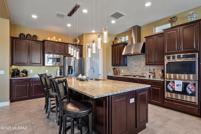 14326 Whitehorn Pl, Marana, AZ 85658 - kitchen featuring stainless steel appliances, wall chimney exhaust hood, a breakfast bar area, light stone countertops, and dark brown cabinetry