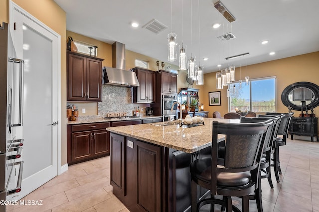 14326 Whitehorn Pl, Marana, AZ 85658 - kitchen featuring wall chimney range hood, stainless steel appliances, a kitchen island with sink, a breakfast bar, and light tile patterned flooring