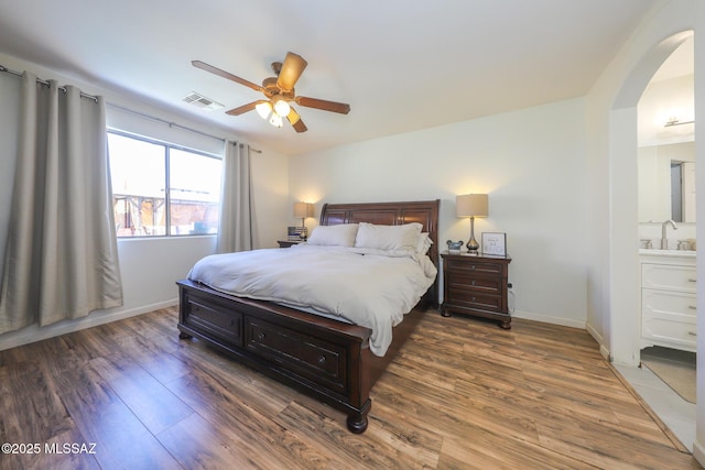 6976 Somerton Dr, Tucson, AZ 85743 - bedroom featuring arched walkways, wood finished floors, a ceiling fan, and ensuite bath