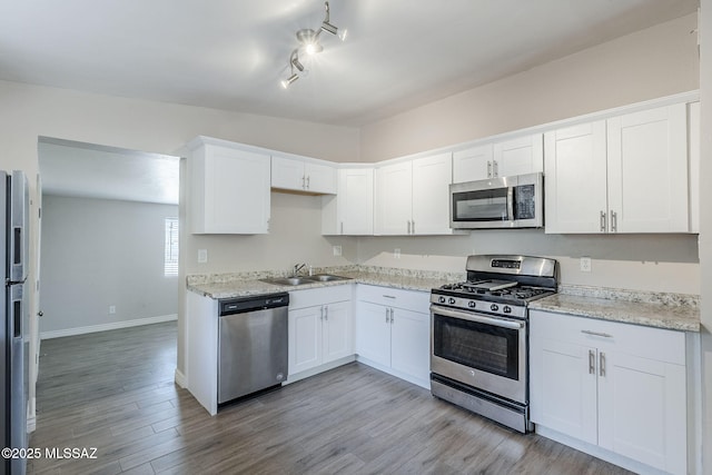 18 E Mac Iver Pl, Tucson, AZ 85705 - kitchen with appliances with stainless steel finishes, white cabinets, light wood finished floors, light stone counters, and rail lighting