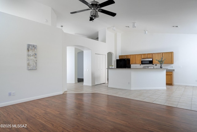 9438 N Weather Hill Dr, Tucson, AZ 85743 - unfurnished living room with arched walkways, high vaulted ceiling, a ceiling fan, and light wood-style floors